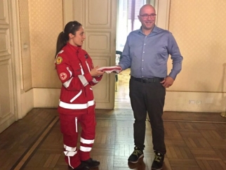 La rappresentante della Croce Rossa di Livorno consegna la bandiera dell'Associazione all'assessore Andrea Morini