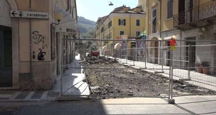 Cantiere in via Verdi a Carrara: scavi, recinzioni e mini-escavatore tra i palazzi del centro.