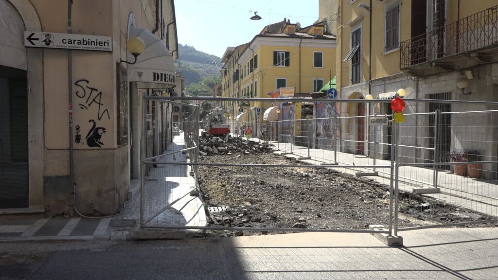 Cantiere in via Verdi a Carrara: scavi, recinzioni e mini-escavatore tra i palazzi del centro.