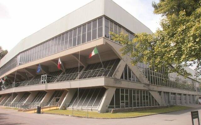 Facciata del palazzetto dello sport a Lucca con bandiere UE, Lucca e Italia