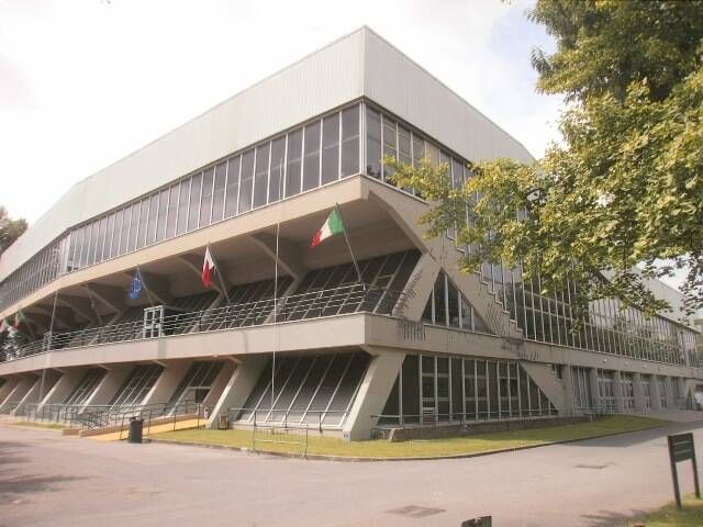 Facciata del palazzetto dello sport a Lucca con bandiere UE, Lucca e Italia