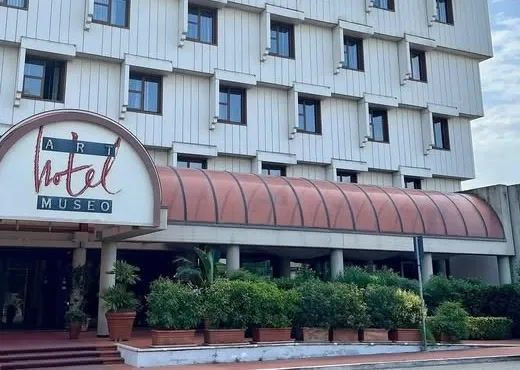 Facciata e ingresso dell’Art Hotel Museo a Prato, in viale della Repubblica, con la pensilina curva e l’insegna rossa