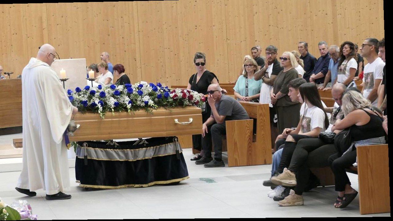 Viareggio, funerale di Linda Martinucci in chiesa al Varignano: bara con fiori, sacerdote e fedeli con magliette bianche — stessa scena, nuova angolazione e inquadratura, volti invariati