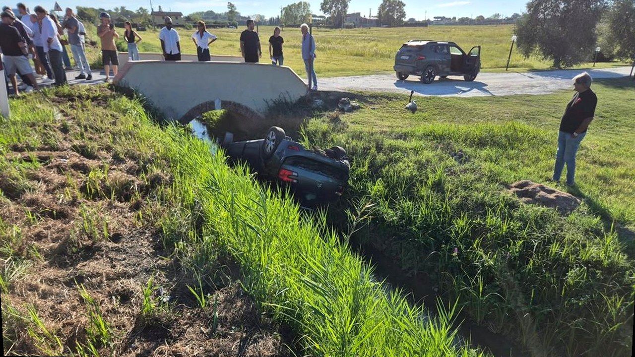 Pisa, via del Brennero: auto ribaltata nel fosso dopo lo scontro — stessa scena, nuova angolazione geometrica (nessun volto alterato)