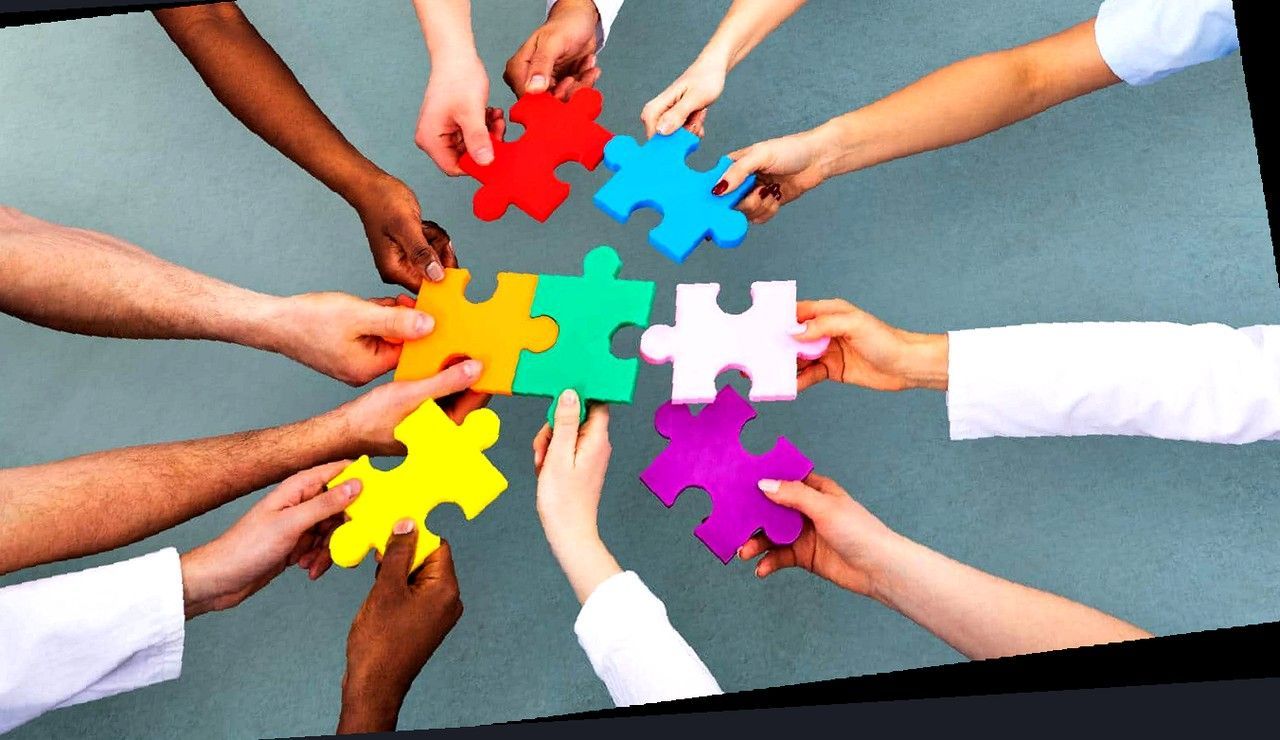 Mani diverse uniscono pezzi di puzzle colorati, metafora di inclusione