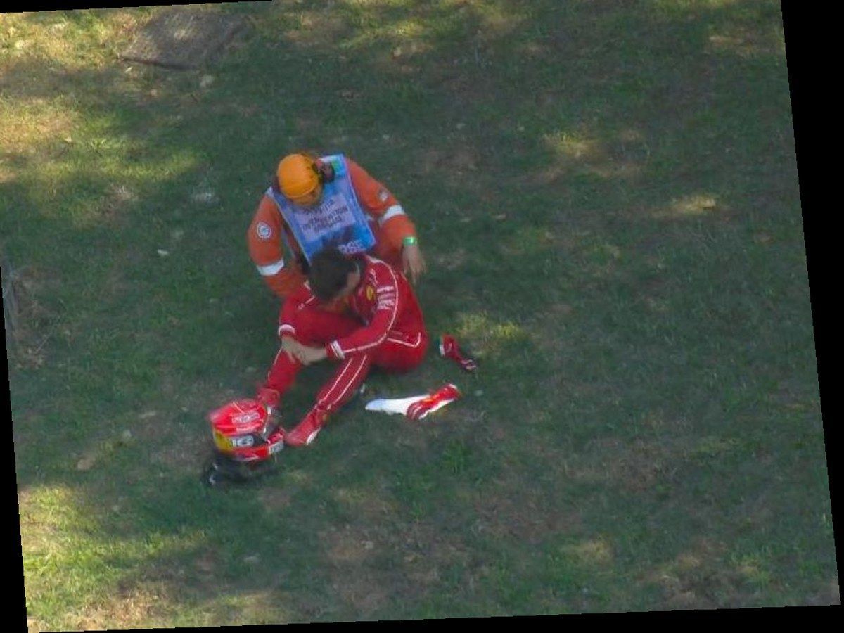 Charles Leclerc in tuta rossa Ferrari seduto sull erba a Monza con casco 16 a terra e marshal Intervention