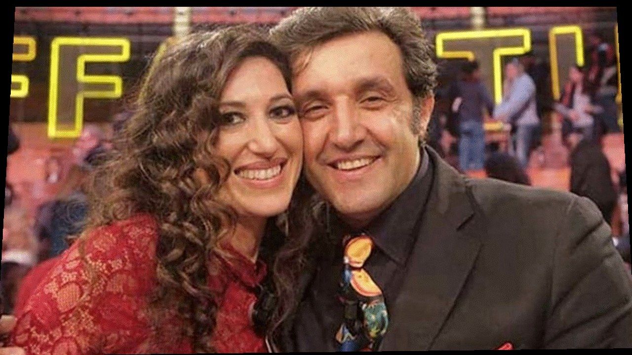 Flavio Insinna e Adriana Riccio nello studio di Affari Tuoi — stessa scena della fonte Bigodino, nuova angolazione geometrica (volti invariati)