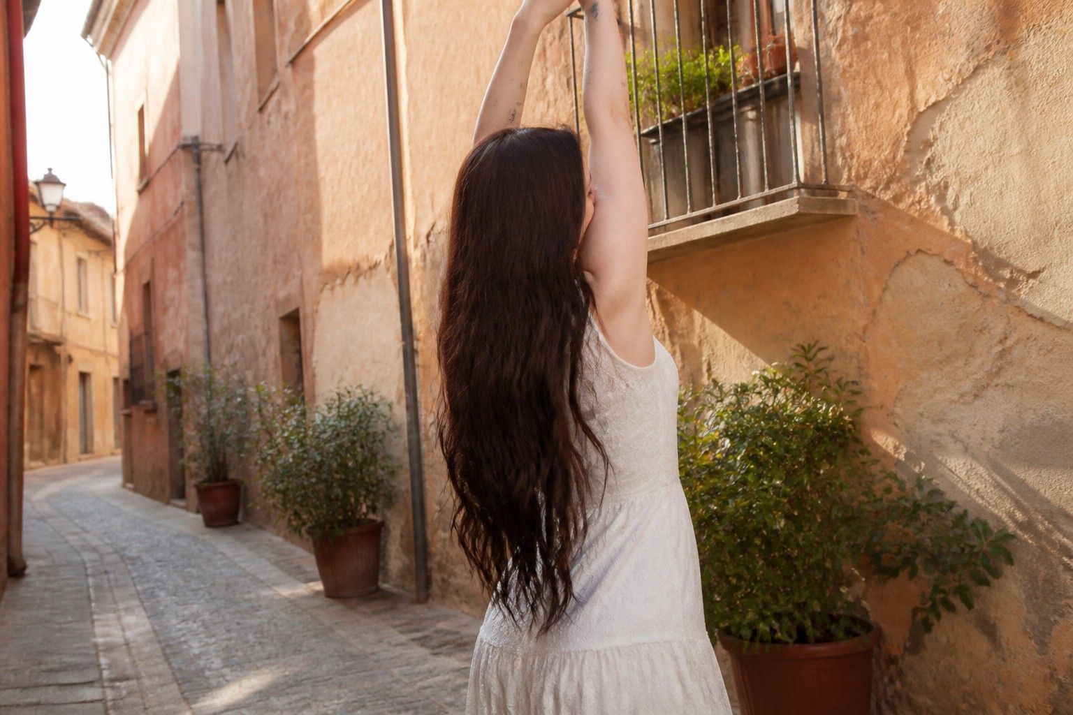 Dove Cameron di spalle in un vicolo italiano, braccia alzate, prima delle nozze con Damiano
