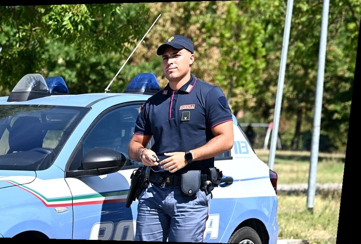 Agente della Polizia di Stato Volanti accanto a un'auto di servizio a Pisa