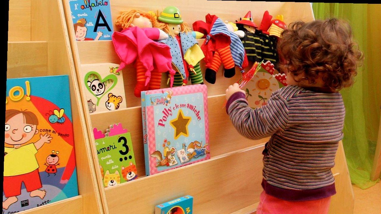 Bambino in asilo davanti allo scaffale dei libri — stessa scena, nuova angolazione e inquadratura