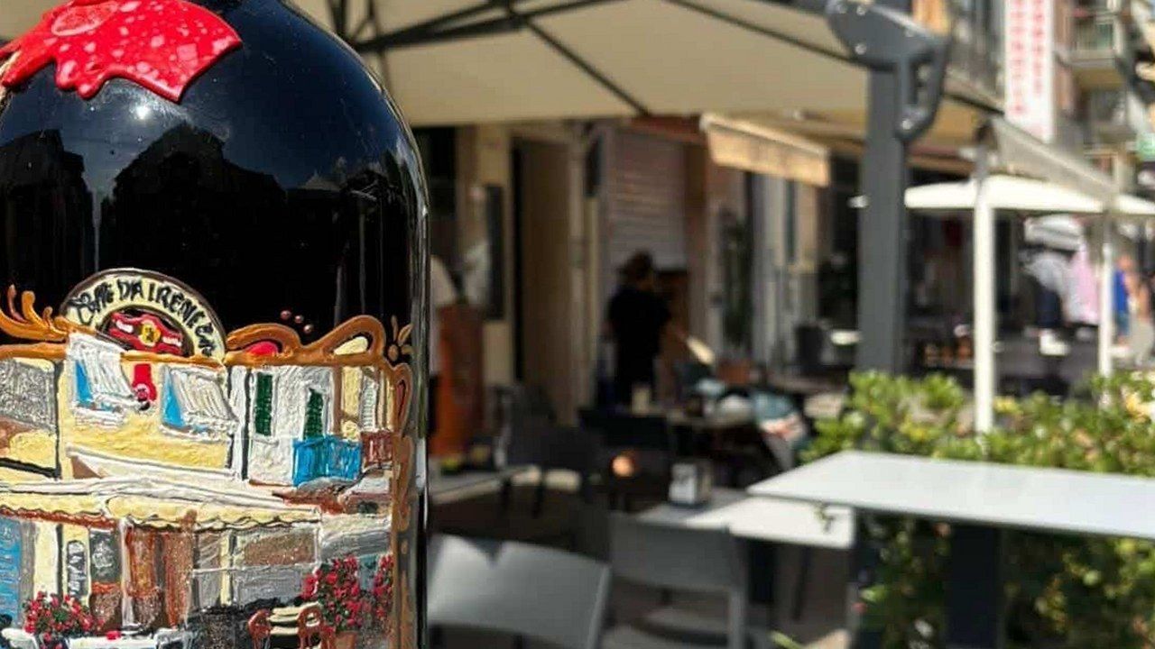 Il Caffè Irene nel Piazzone di Viareggio, con i tavolini sotto gli ombrelloni e la bottiglia dipinta con l'insegna del bar