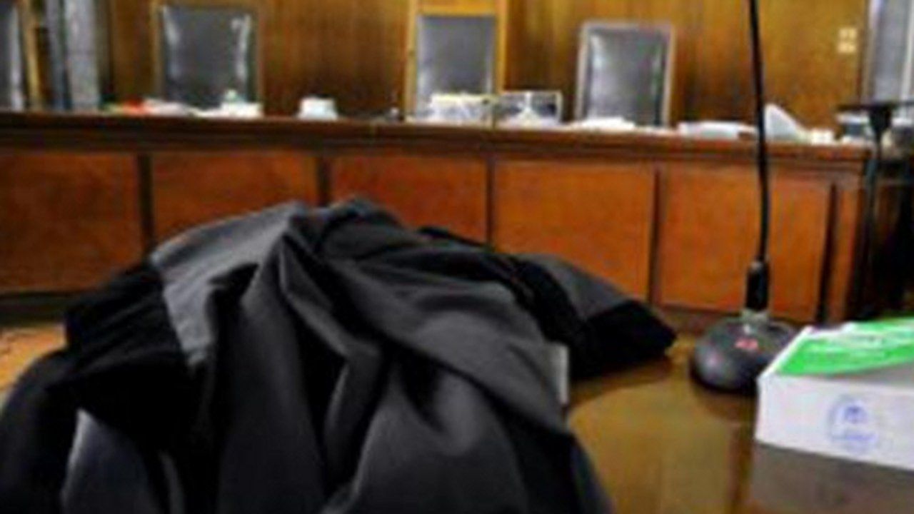 Aula di tribunale con toga e scritte «La legge è uguale per tutti» — angolazione geometrica modificata, senza alterazione di volti