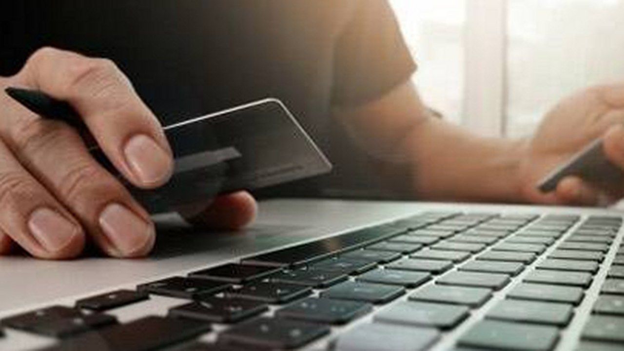 Mani con carta di credito, laptop e smartphone: immagine di repertorio legata a pagamenti e operazioni online
