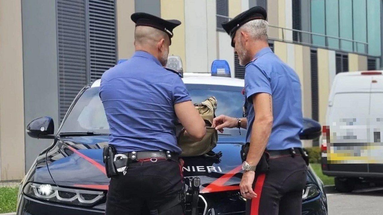 Carabinieri ispezionano uno zaino sul cofano di una volante durante un controllo