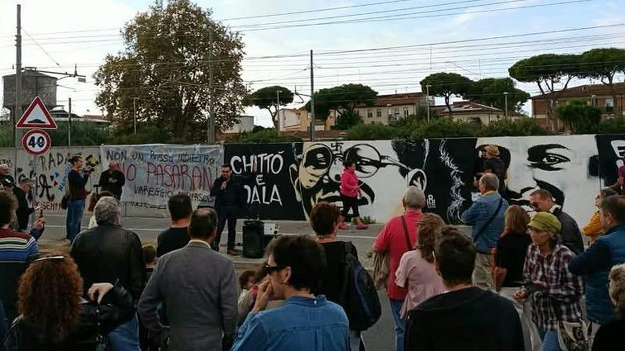 Cittadini radunati davanti al murale dedicato a Didala e Chittò lungo la ferrovia a Viareggio durante il restauro (foto TGRegione)