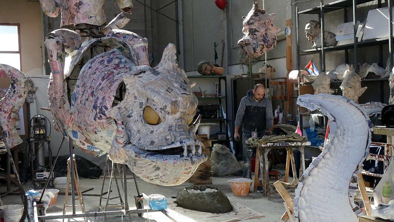 Un costruttore al lavoro in un hangar della Cittadella del Carnevale di Viareggio tra le sculture in cartapesta (foto La Nazione)
