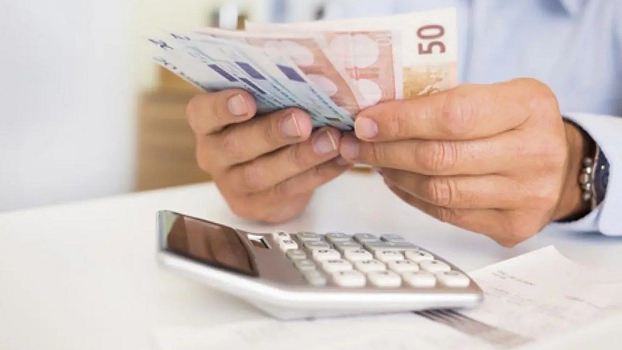 Mani che contano banconote da 50 euro accanto a una calcolatrice: famiglie lucchesi sempre più indebitate