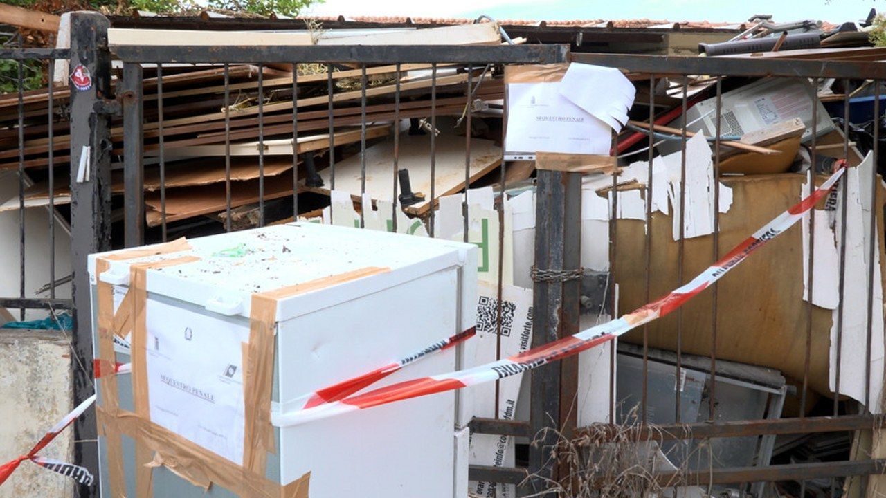 Il giardino dell'immobile di via Giannessi a Viareggio con i rifiuti sotto sequestro e il nastro bianco e rosso — angolazione e inquadratura rielaborate